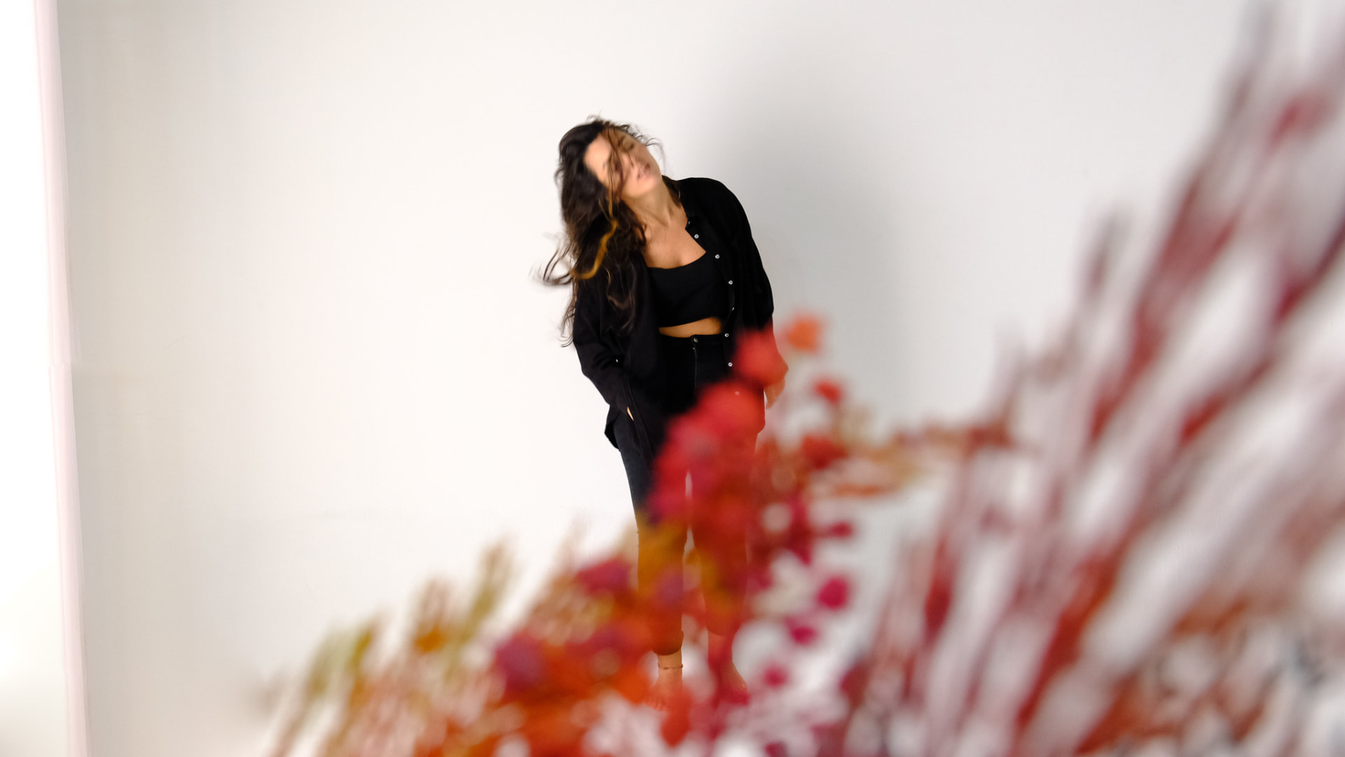 Carolina Zingler em movimento atrás de flores vermelhas