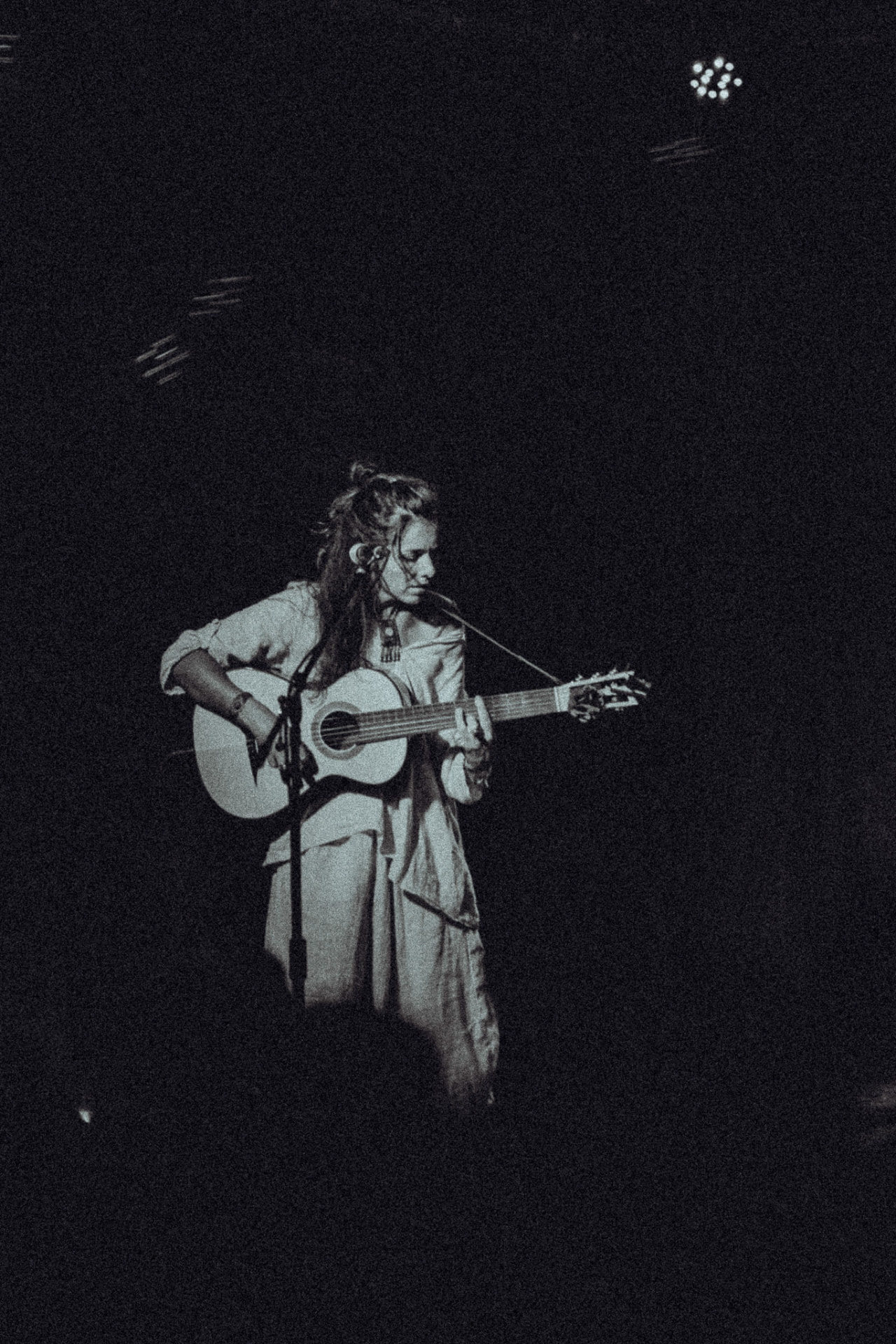 Carolina Zingler sozinha em palco com violão, preto e branco